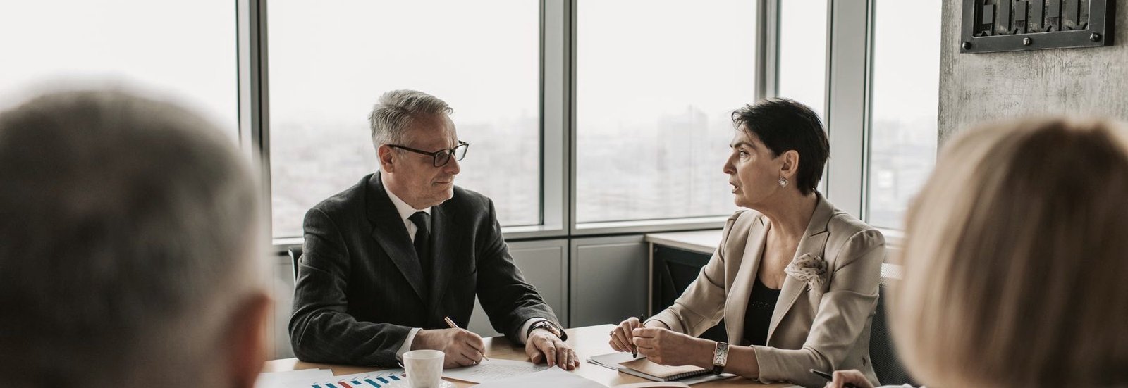 Two advisors in discussion across a table of printed analysis.